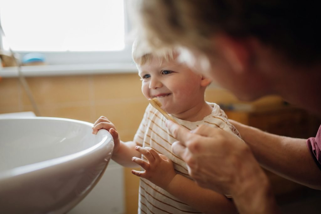 Father brushing little baby boy's teeth in the morning. Morning dental hygiene for toddlers.