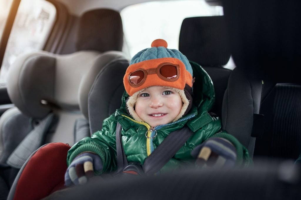 Happy baby boy sitting in baby car seat