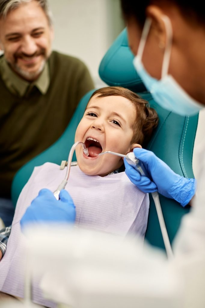 Small kid getting his teeth checked by dentist at dental clinic.